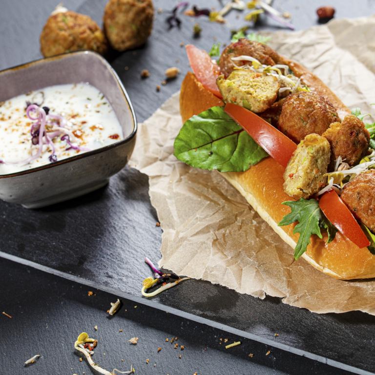 Vegetarischer Gemüsebällchen Hot Dog mit Gurke, Joghurt und Wildkräutersalat Vegetarischer Gemüsebällchen Hot Dog